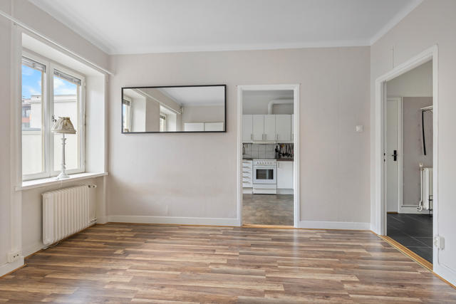 Allrum med djupa fönstersmygar och fönsterbrädor. Vy mot kök och hall. 