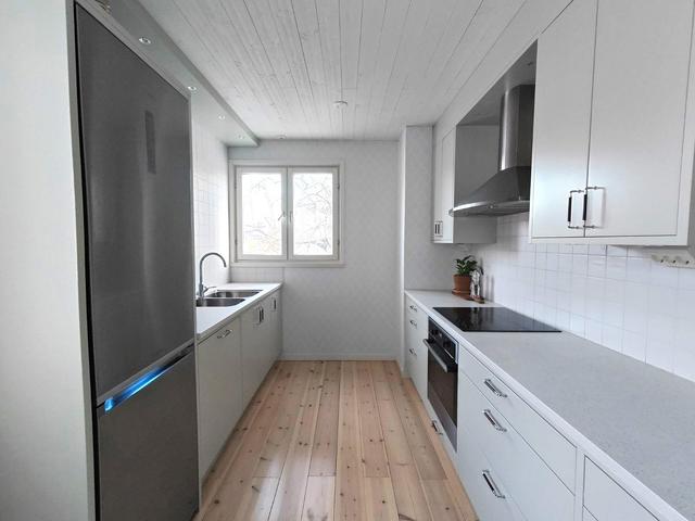 Det vackra trägolvet harmoniserar fint med kökets stil och kulör.