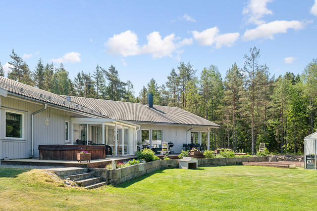 Baksidan huset med stor terrass i sydvästläge, snyggt anlagd trädgård.