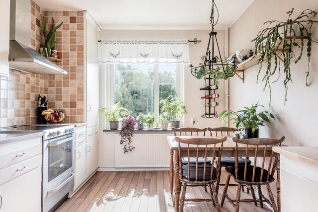 Ljust och trevligt kök med ljusa skåpsluckor och naturlig plats för matbordet. 