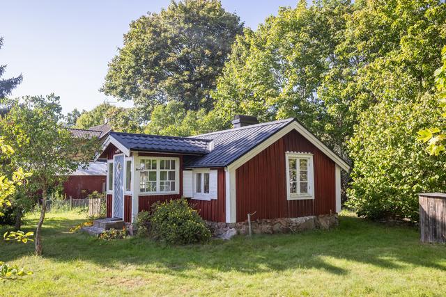 Litet rött hus med vita knutar och nytt tak