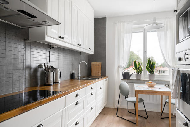 Fräscht kök med plats för matgrupp vid fönstret.