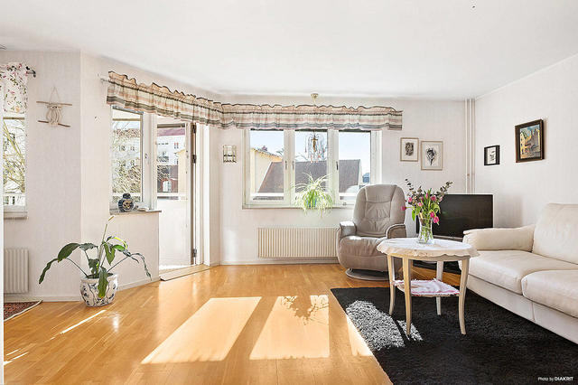 Ljust vardagsrum med öppen planlösning mot köket, matsalen och utgång till balkong/loftgång