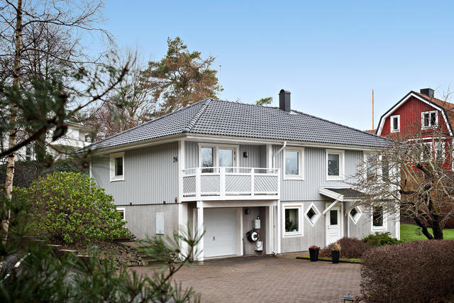Stor parkeringsplats med plats för flertalet bilar och garage som nås från huset