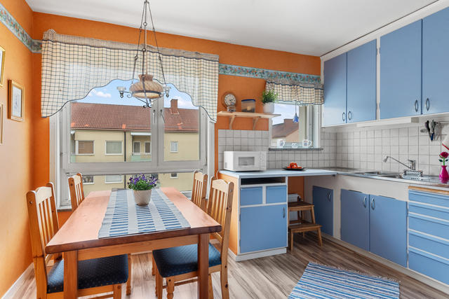 Vacker glasdörr som leder in till det bekväma köket. gott om plats för ett rejält matbord och arbetsytor för mat och bak. Blå luckor, rostfri diskbänk med tre hoar, 10x10 cm kakel som stänkskydd ovanför arbetsbänkar i laminat. Två fönster mot öster, tapet med bård och laminat på golvet.