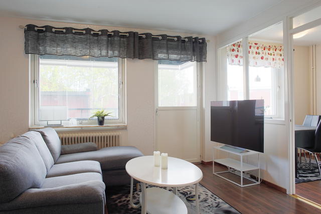 Allrum med soffa, utgång till den inglasade balkongen och vy mot köket