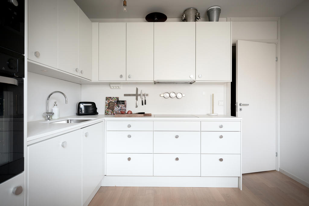 Köksluckor i modern, ljusgrå nyans, maskinell utrustning från Husqvarna med integrerad kyl och frys, häll, fläkt, integrerad diskmaskin samt ugn och micro.