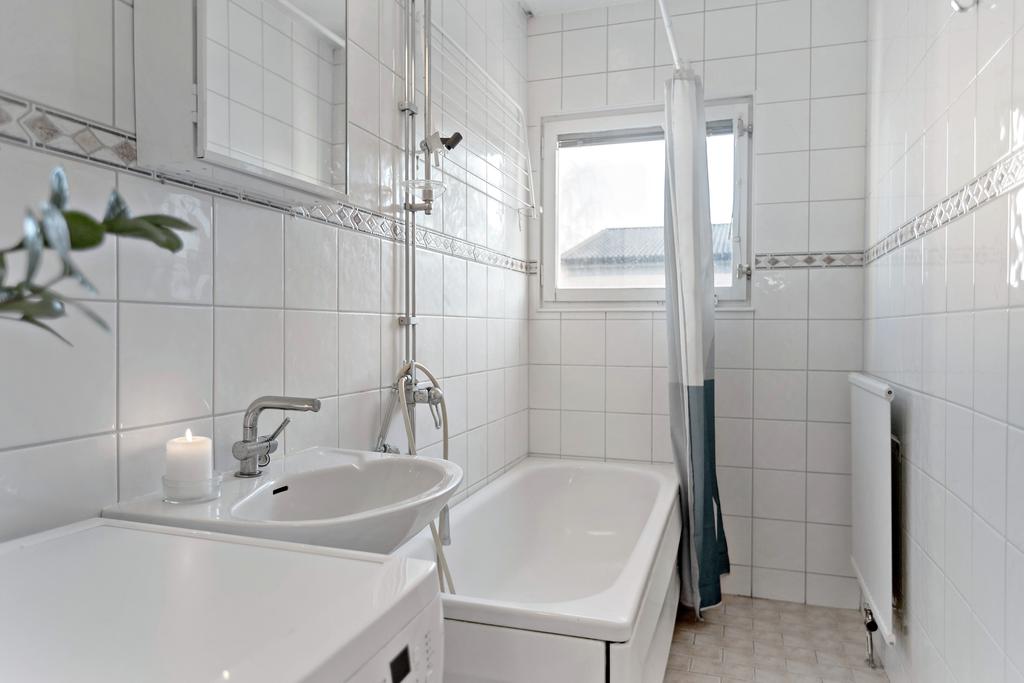Stort badrum med kakel och klinker samt tvättmaskin som ingår i köpet