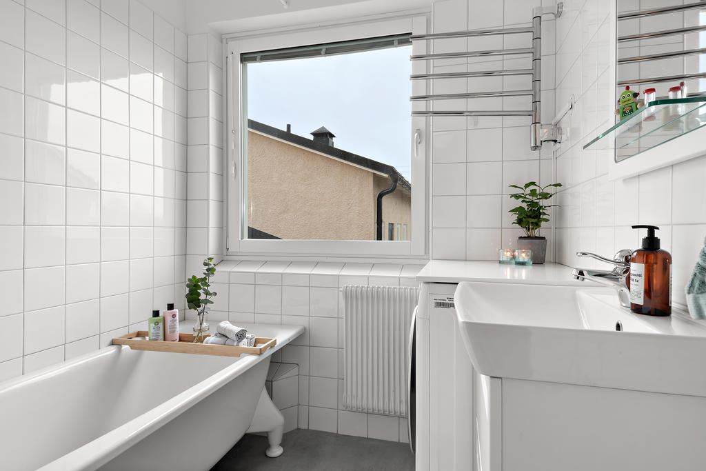 Badrum med badkar och tvättmaskin. Nytt golv i microcement
