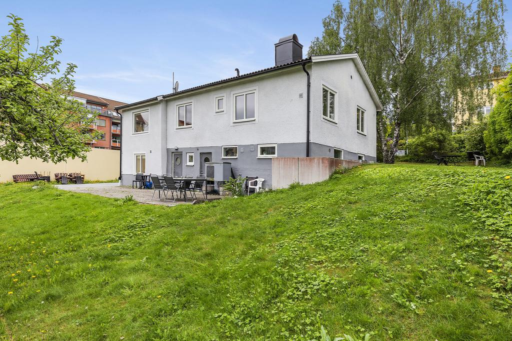 Vy mot fasad på husets baksida samt två ingångar till källardelen