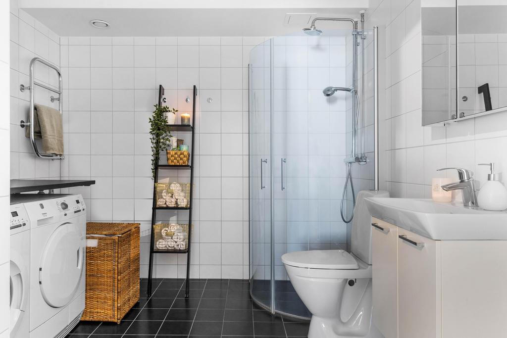 Till höger om hallen finns bostadens helkaklade badrum med tvättutrymme.