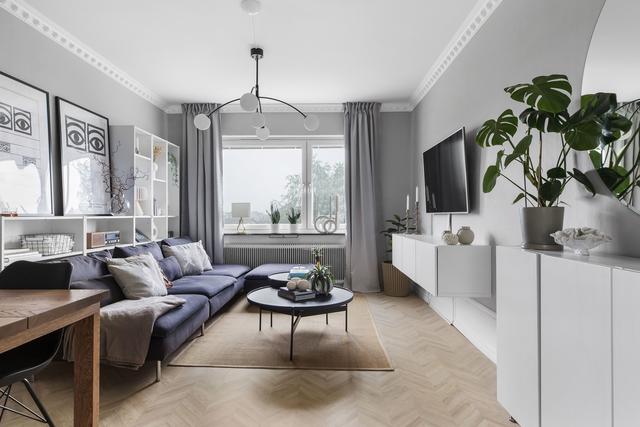 Vardagsrum med ljust golv och gråa väggar