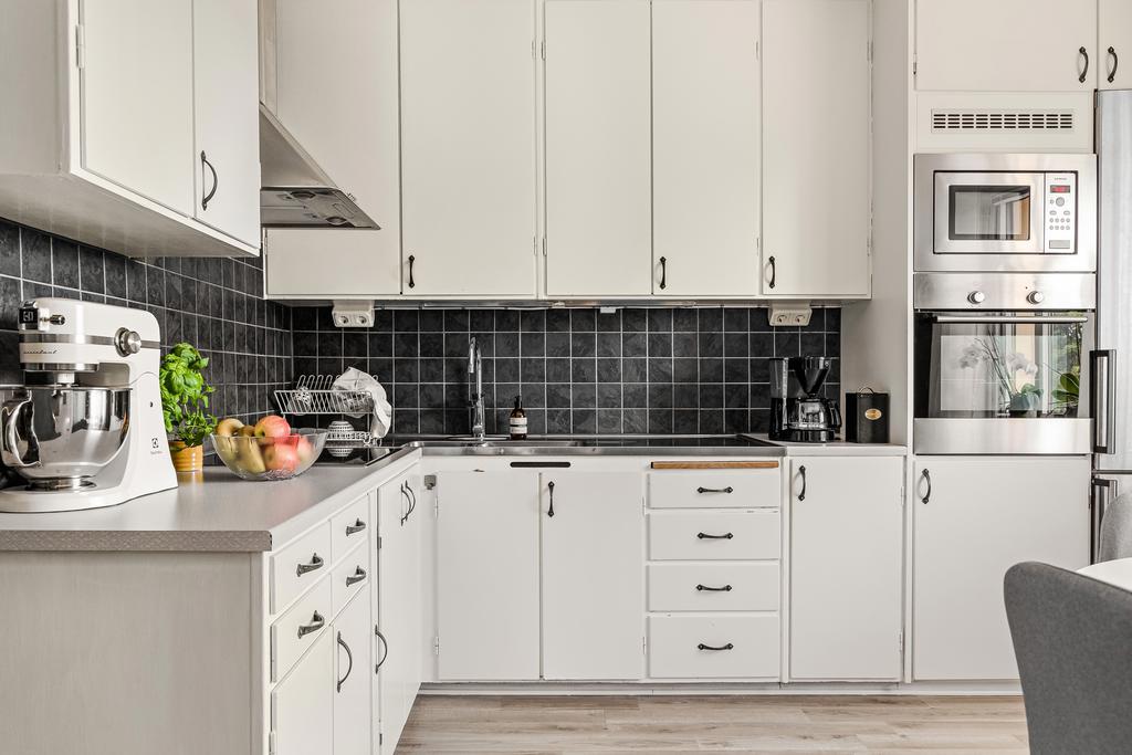 Köket är fint med tidslös design. Vita köksluckor i harmoni med väggarnas lugna gröna nyans skapar en känsla av harmoni.