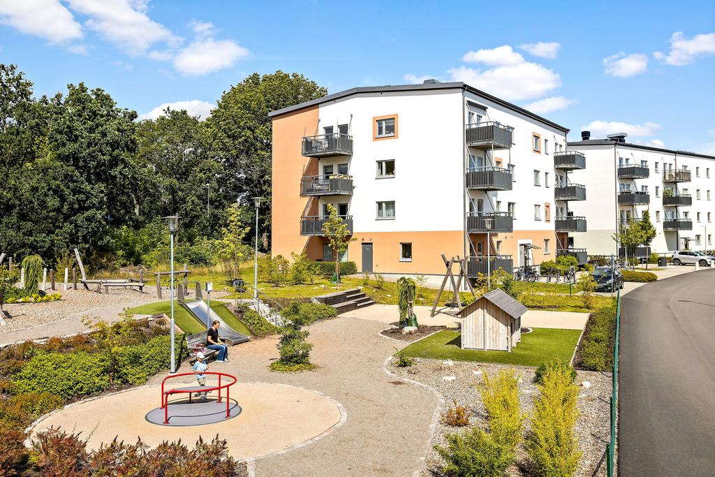 Vacker fasad med grön omgivning och lekplats för barnen