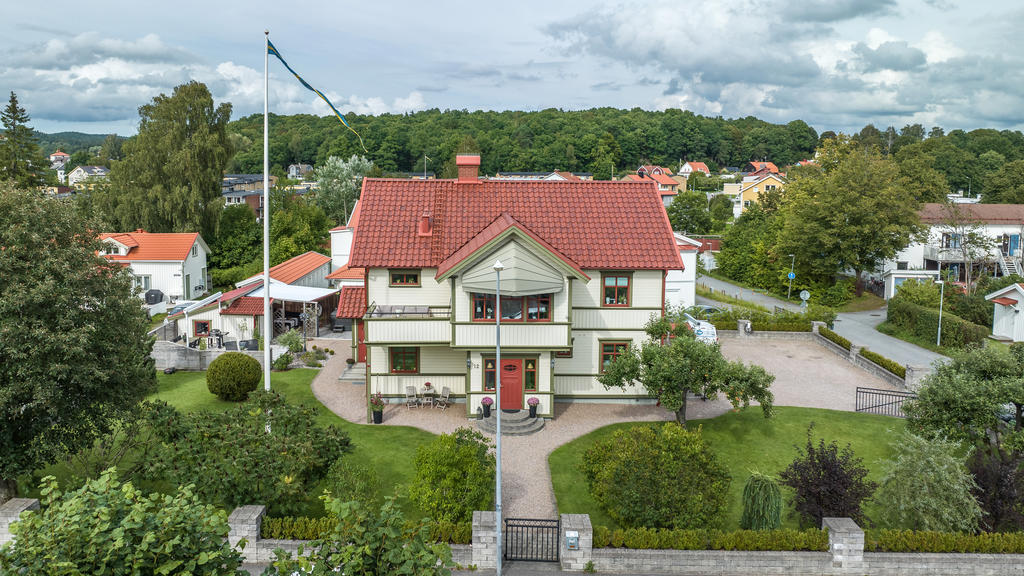Entrésida med vacker mur, uthus med altaner, stor parkeringsyta. 