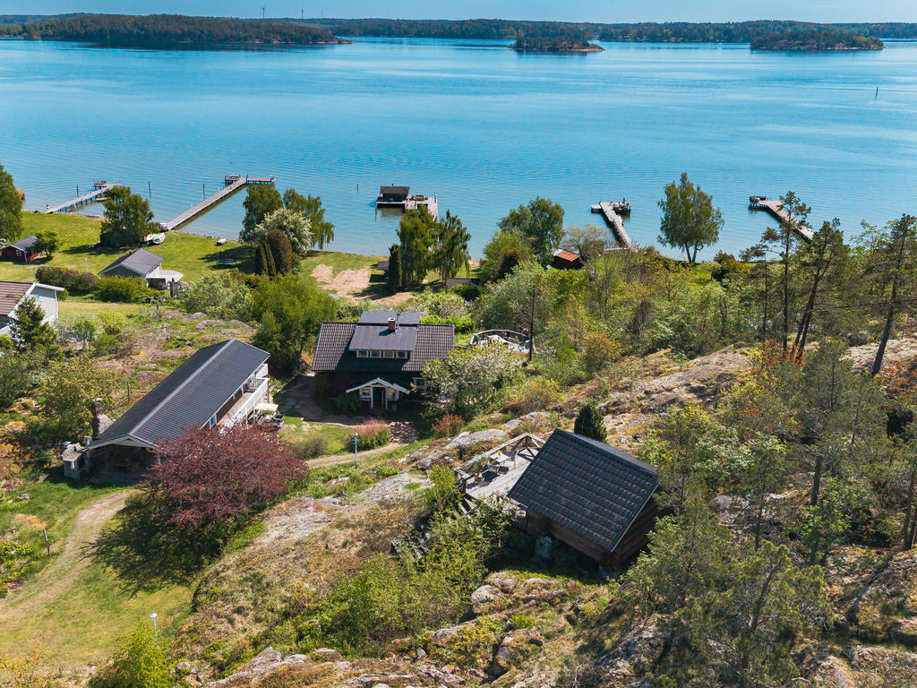 Överblicksbild - huvudhus, lång gäststuga, gäststugan på berget, lilla friggeboden nere vid vattnet och bastun ute på bryggan. 