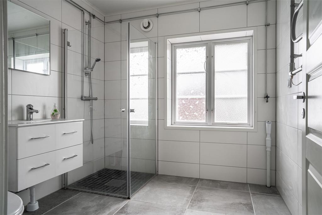 Hlekaklat badrum med dusch, kommod, wc och förberett för tvättmaskin.