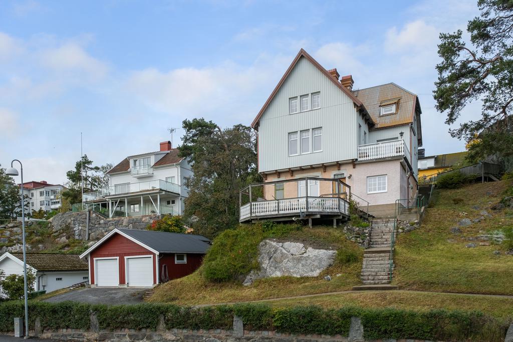 Framsida trädgård. Trappor till entréplanet till höger om bostadshuset.