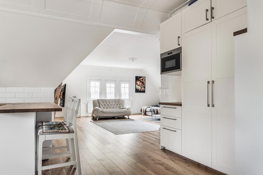 Integrerad kyl och frys. Mikrovågsugn och servingsbänk. Vardagsrum i bakgrunden.