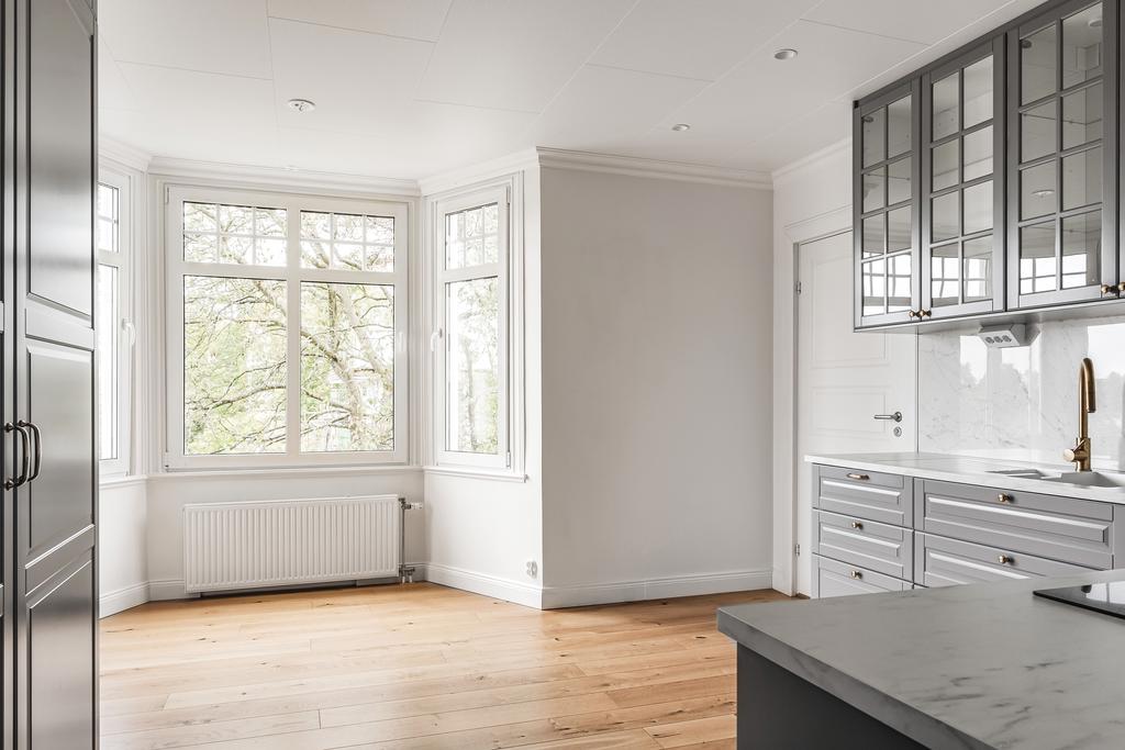 Köket med detaljer som blandare i mässing, infällda spotlights och vitrinskåp.