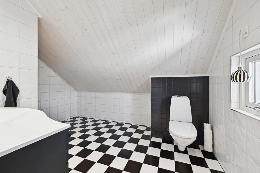 Badrum övre plan med vägghängd wc, gott om plats och ett litet sött fönster.