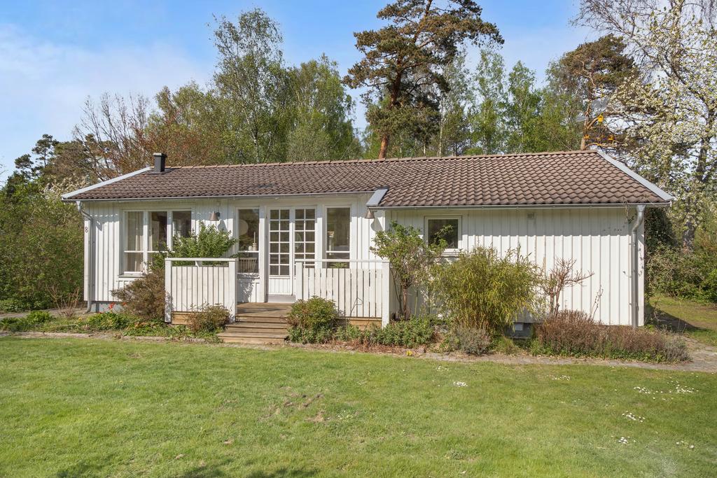 Fritidshusets framsida har en mysig veranda och stora fönster.