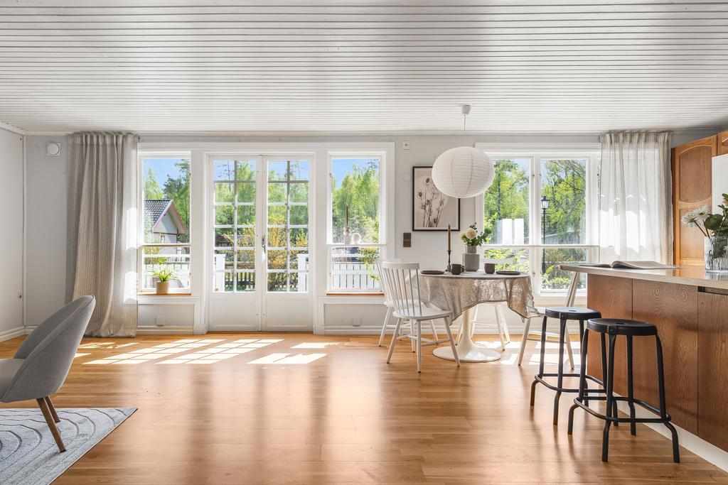 Vardagsrummet karaktäriseras av en elegant ekparkett, ett rikligt ljusinsläpp och en rymlig yta som rymmer både soffgrupp och matmöblemang
