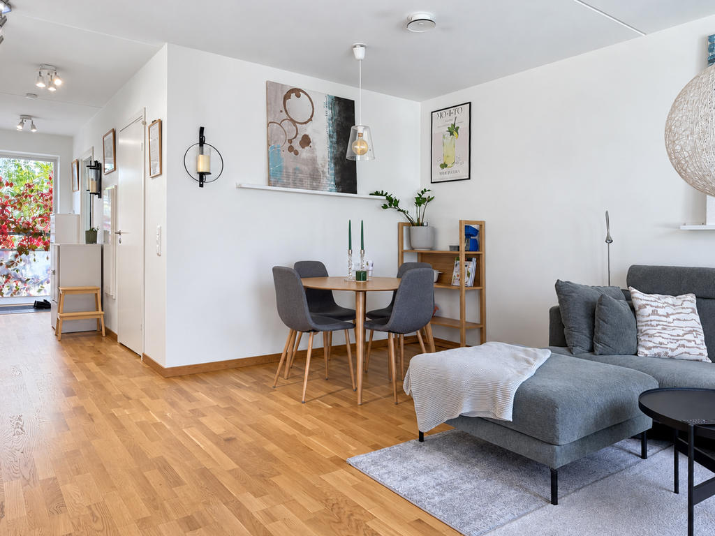 Kök och vardagsrum i öppen planlösning mot hall.