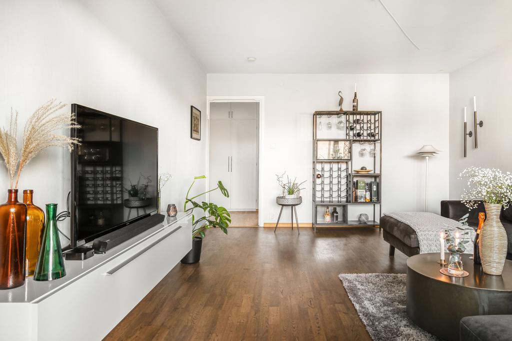  I vardagsrummet finns det gott om plats för både soffgrupp och extra matbord för den som önskar. Ett mörkare laminatgolv kombineras med vitmålade väggar.