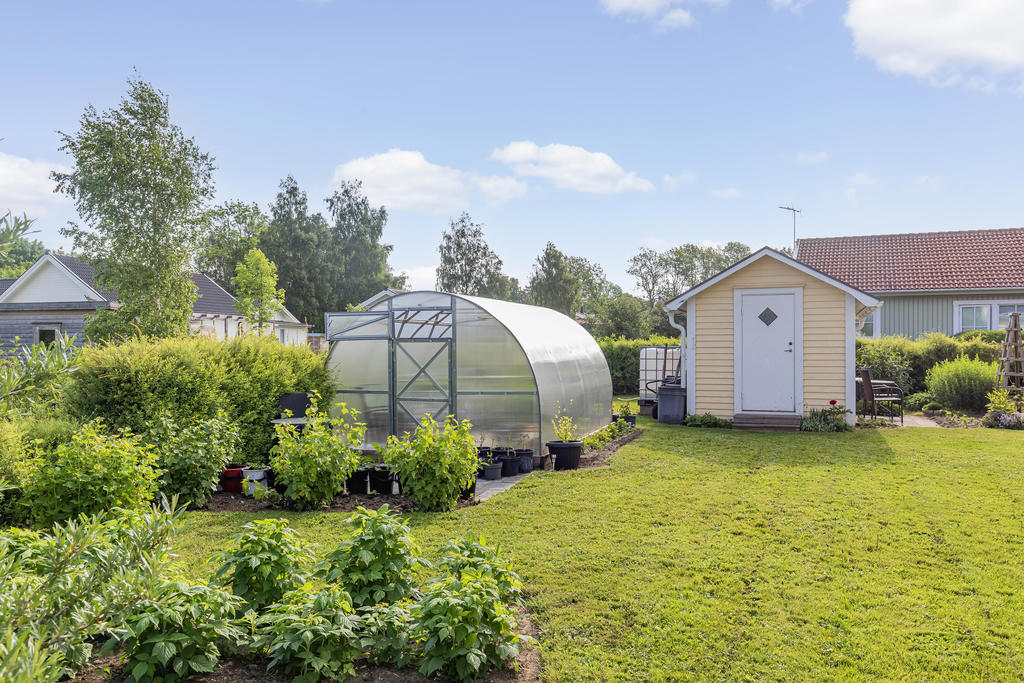 Trädgård med tunnelväxthus och gästhus