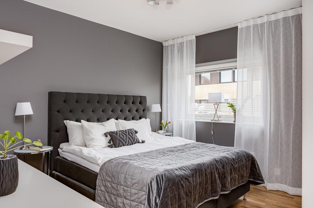 Bostadens sovrum bjuder in till ro och avkoppling med sin lugna atmosfär och grå färgsättning.