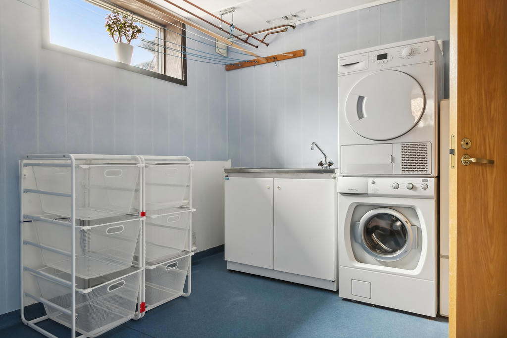 Tvättstuga med tvättmaskin och torktumlare samt linor att hänga tvätt