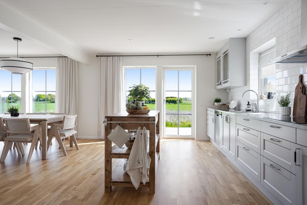 Stilrent kök med öppen planlösning mot matplats och vardagsrum