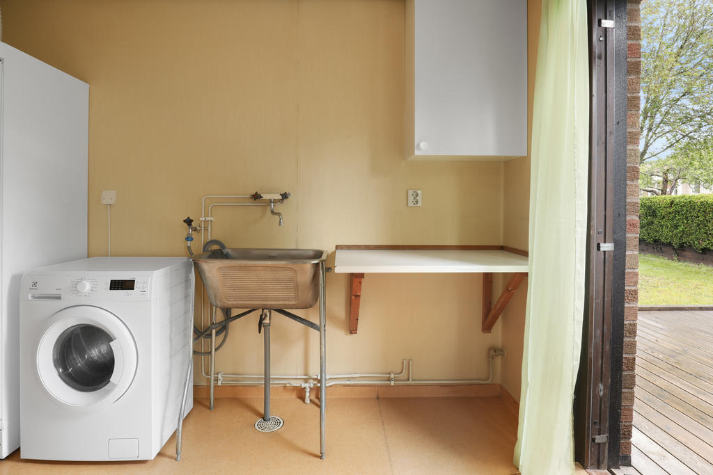 Tvättstuga med praktisk djup diskho. Här kliver du rakt ut på uteplatsen och det är smidigt att hänga tvätten ute. 