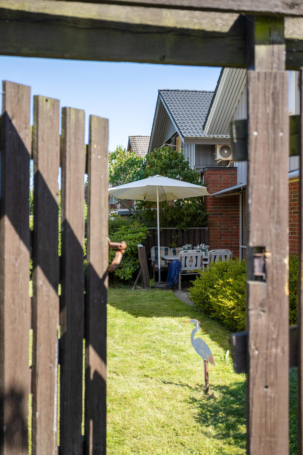 Grinden gör det möjligt att nå trädgården från utsidan. På andra sidan staketet ligger områdets lekplats