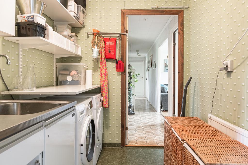 En funktionell tvättstuga där vardagens bestyr får sin givna plats. Gott om hyllor och arbetsyta.