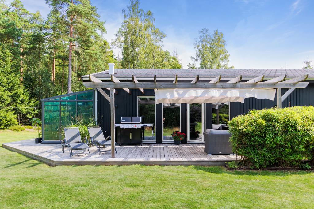 Tomten är inramad av tät skog och grönska, vilket ger ett naturligt insynsskydd och skapar en fridfull atmosfär 