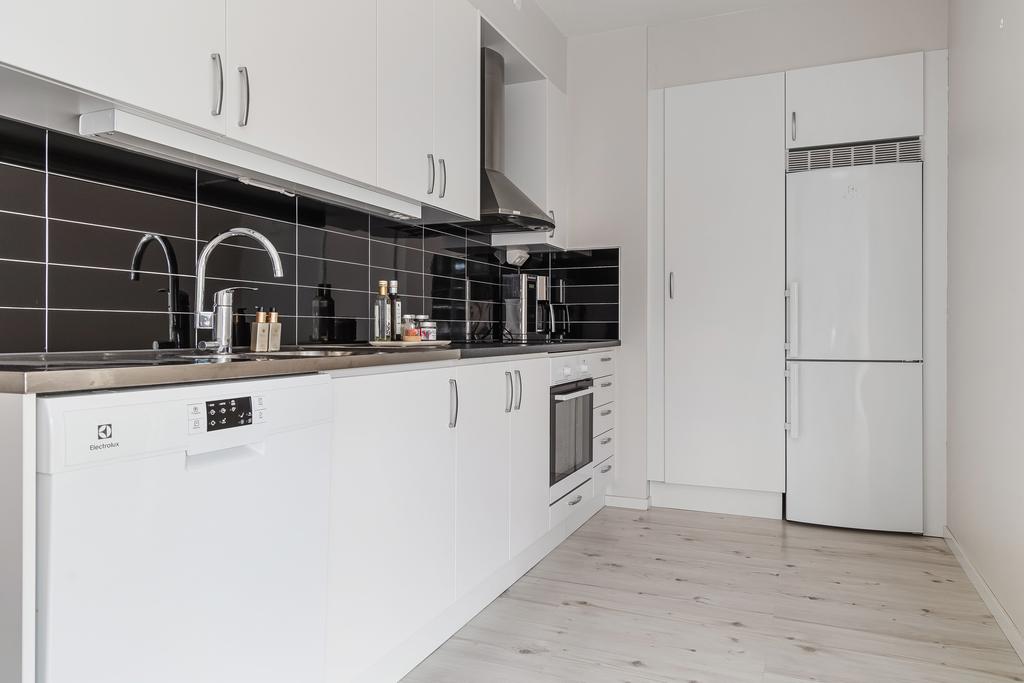 Köket har snygg kontrast mellan vita skåpluckor och svart kakel ovanför arbetsytorna 