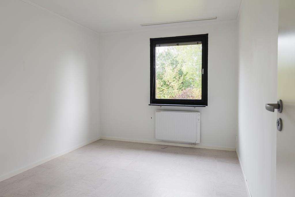 Insynsskyddat sovrum på nedre plan med grön utsikt