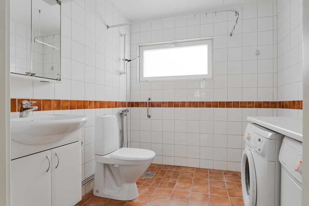 Helkaklat badrum med tvättmaskin och torktumlare för extra bekvämlighet