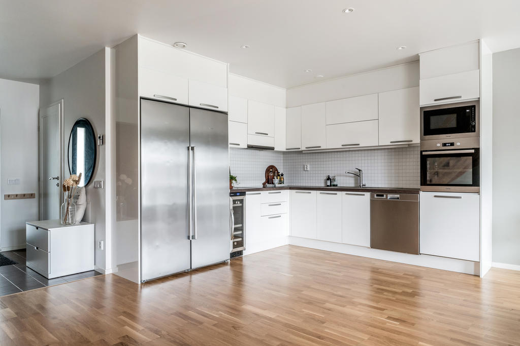 Stilrent & fullutrustat kök med ljusa skåpsluckor och kyl och frys i fulla höjder. 