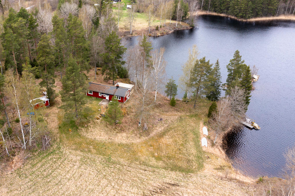 Sjötomt med bostadshus med altan under tak, badplatser och förråd. 
