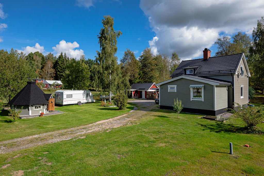 Rymlig trädgård med bastukåta, uthus och uteplatser