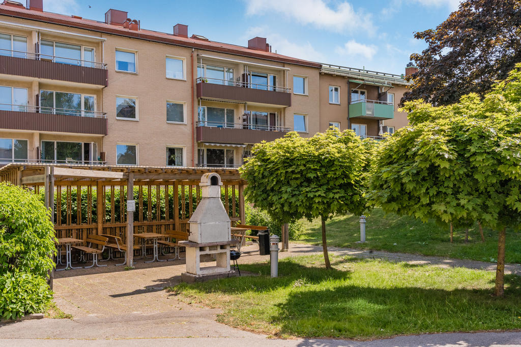Gemensam grillplats med bänkar under en skyddande pergola på innergården.
