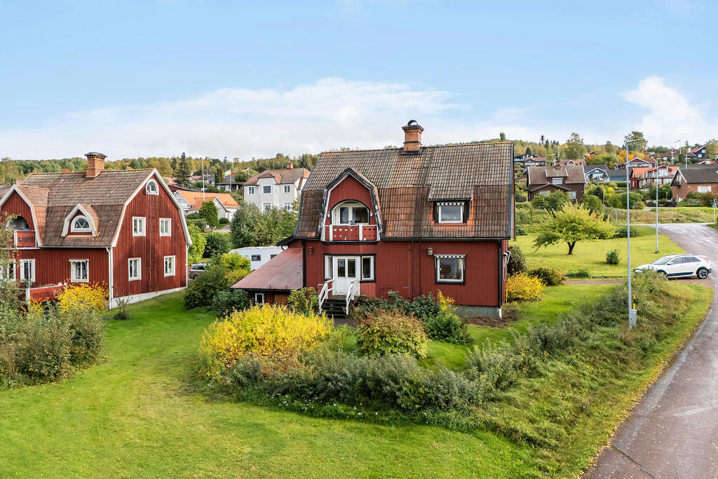 Baksidan med balkong mot Siljan, utgång till altan från entréplan och dörr in till garageverkstaden.   
