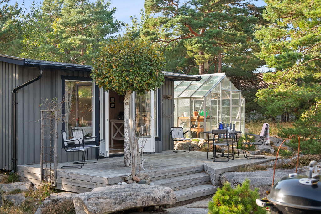Gästhus med dubbla glasdörrar och terrass framför.