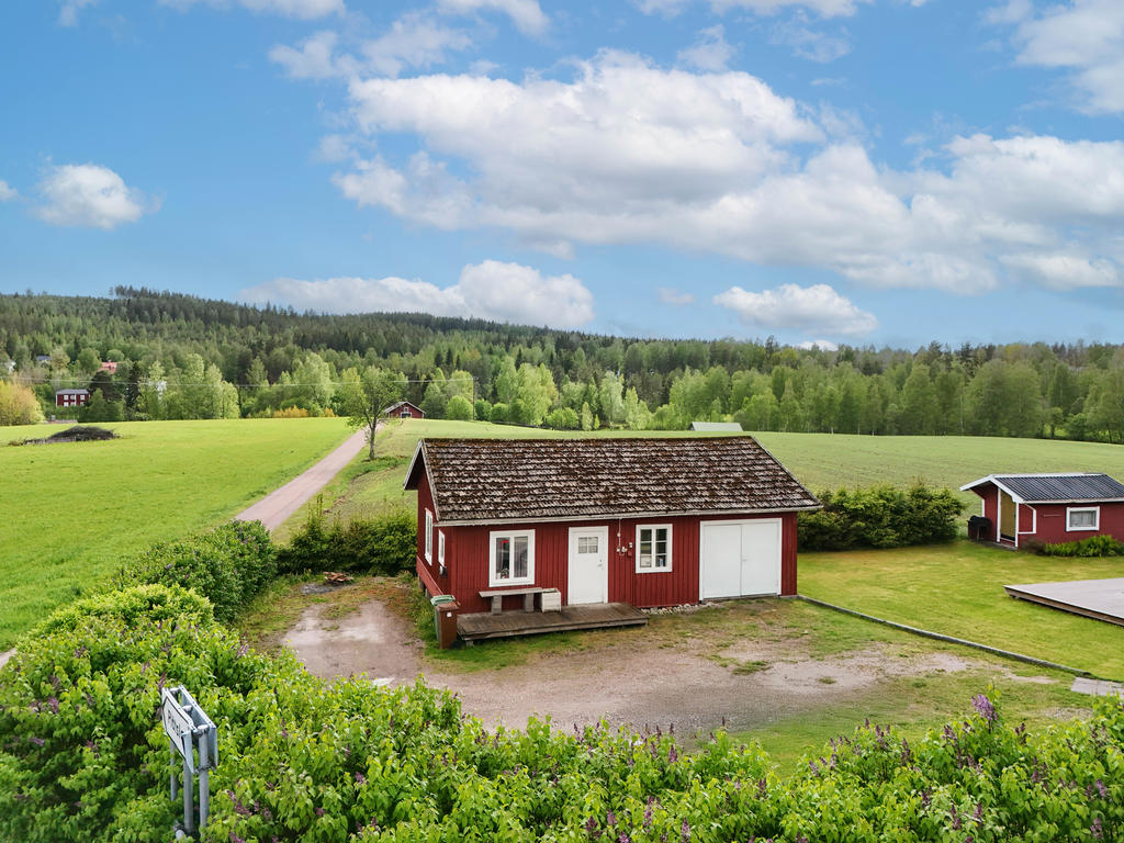 Uthus med el-bilsladdare och lekstuga i tomtens hörna. 