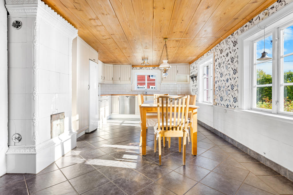 Ljust kök med kakelugn och plats för matbord