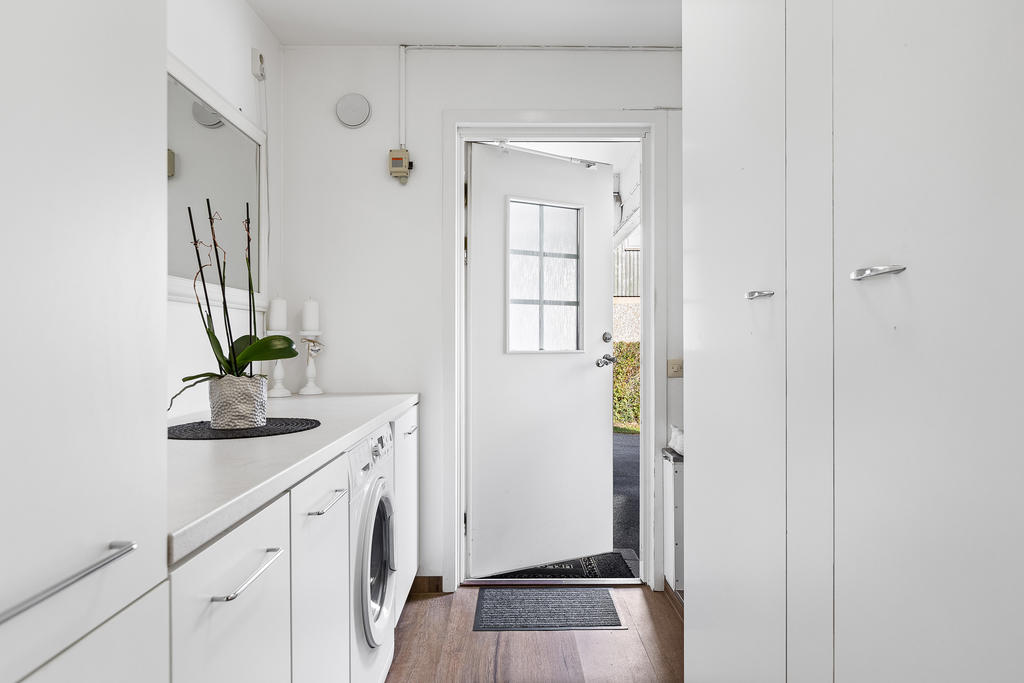 Tvättstuga med laminatgolv, tvättmaskin, klädavhängning och groventré