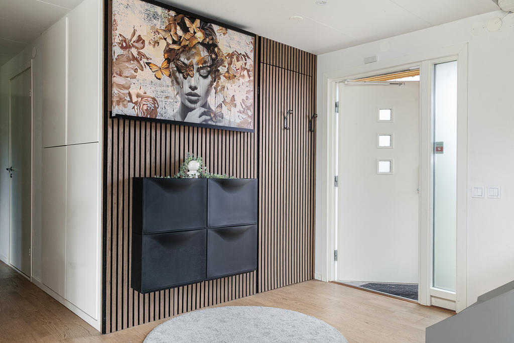 Huvudentré med med trapphall mot öppen planlösning och gästtoalett bakom vacker akustikpanel